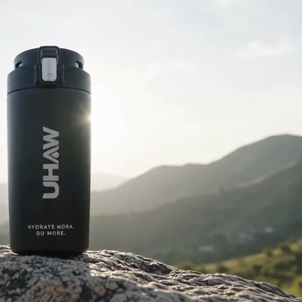 Black tumbler standing on a rock with mountains behind