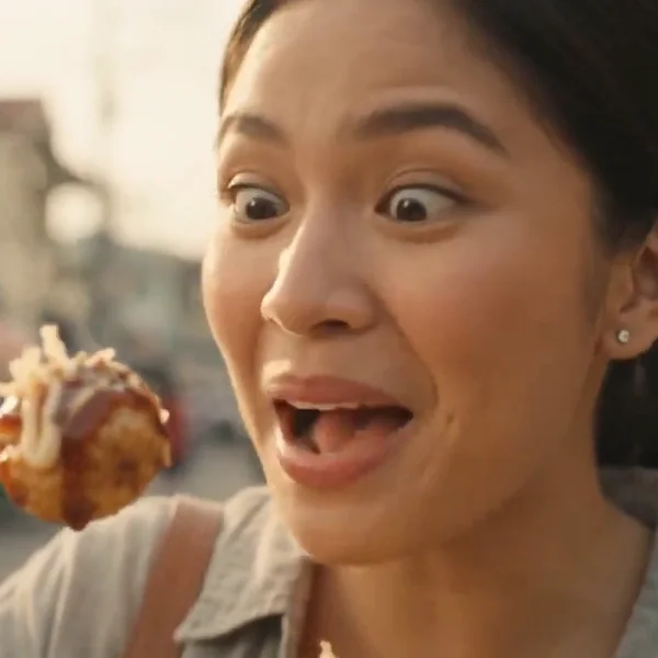Woman looking amazed at a piece of takoyaki